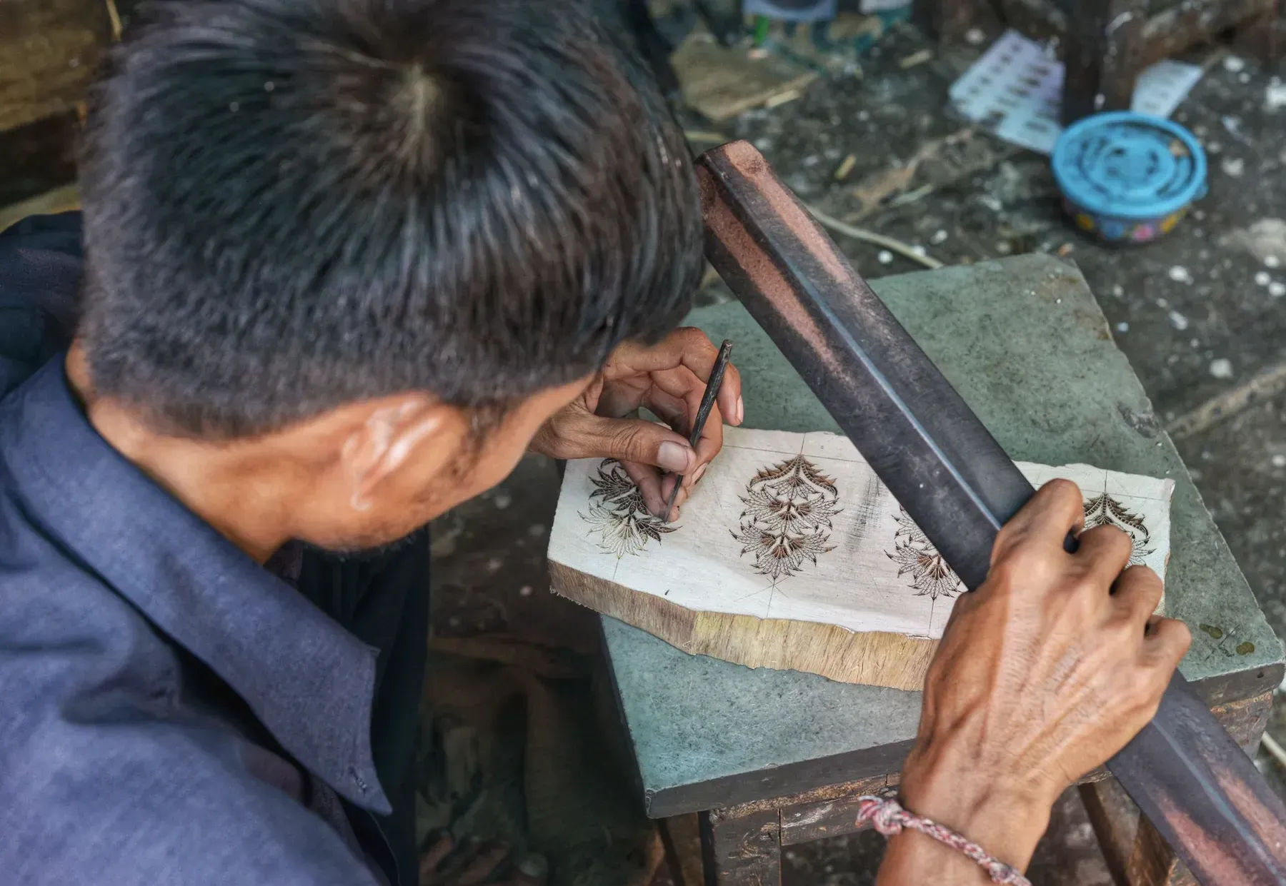 A block carver cutting a floral motif into wood