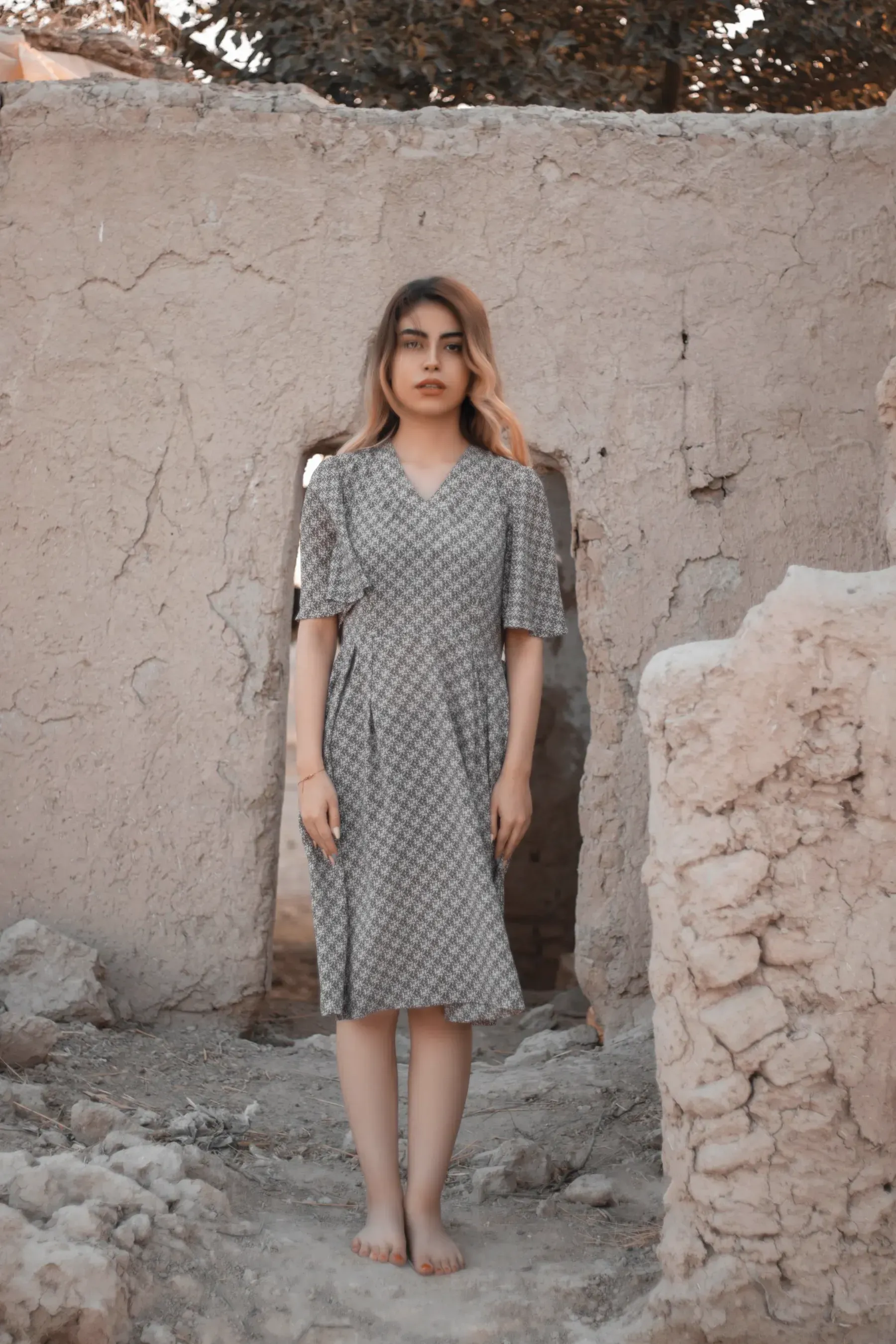 The Slate Bagru Midi Dress, full length, standing in a ruined courtyard